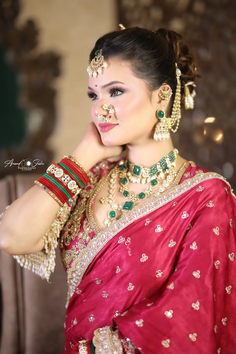 Traditional bridal makeup by Shweta Kadu – bride in a red silk saree with nath, maang tikka and emerald jewellery